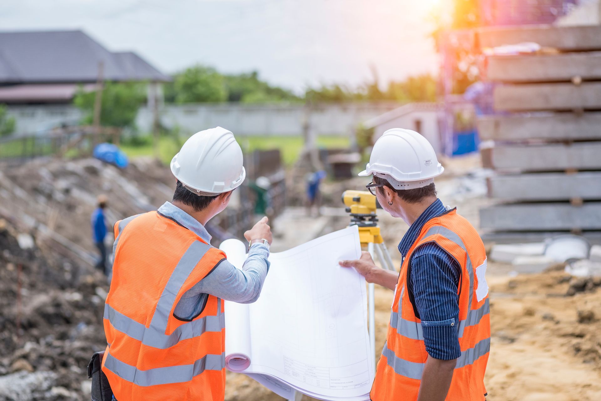 Two construction workers are looking at a blueprint at a construction site.