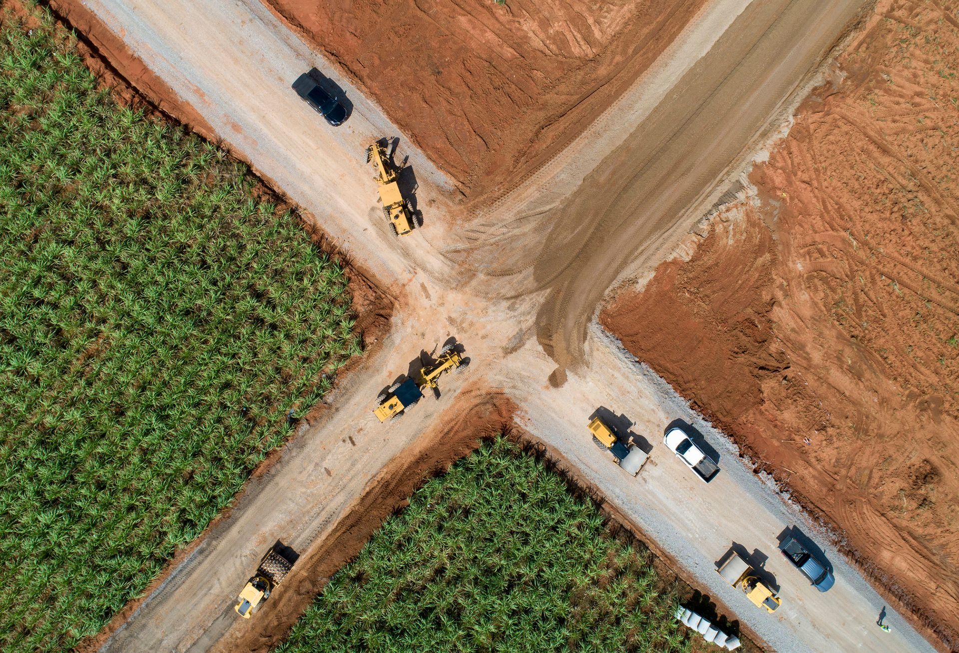 A group of cars are driving down a dirt road.