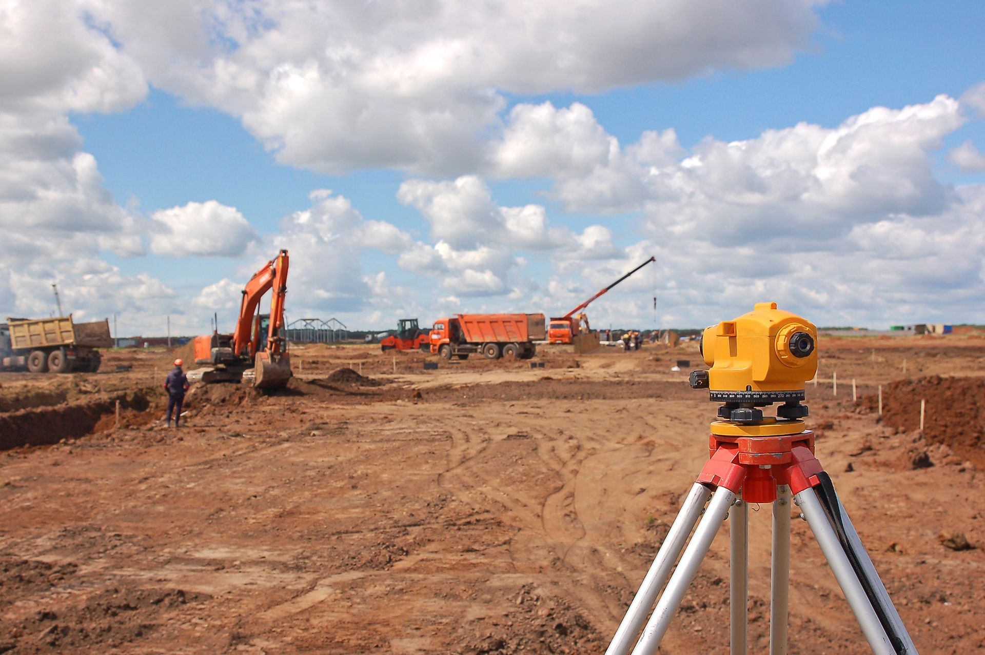 A construction site with a lot of machinery and a tripod in the foreground.