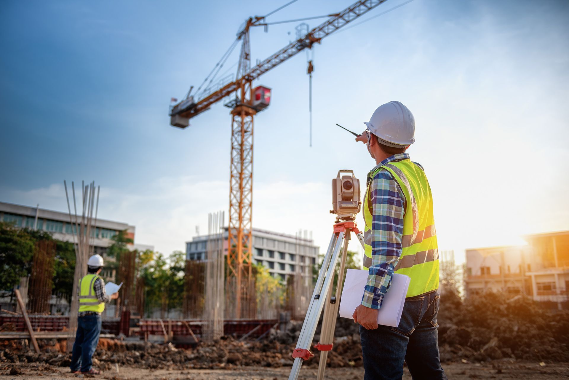 A construction worker is standing in front of a crane at a construction site.