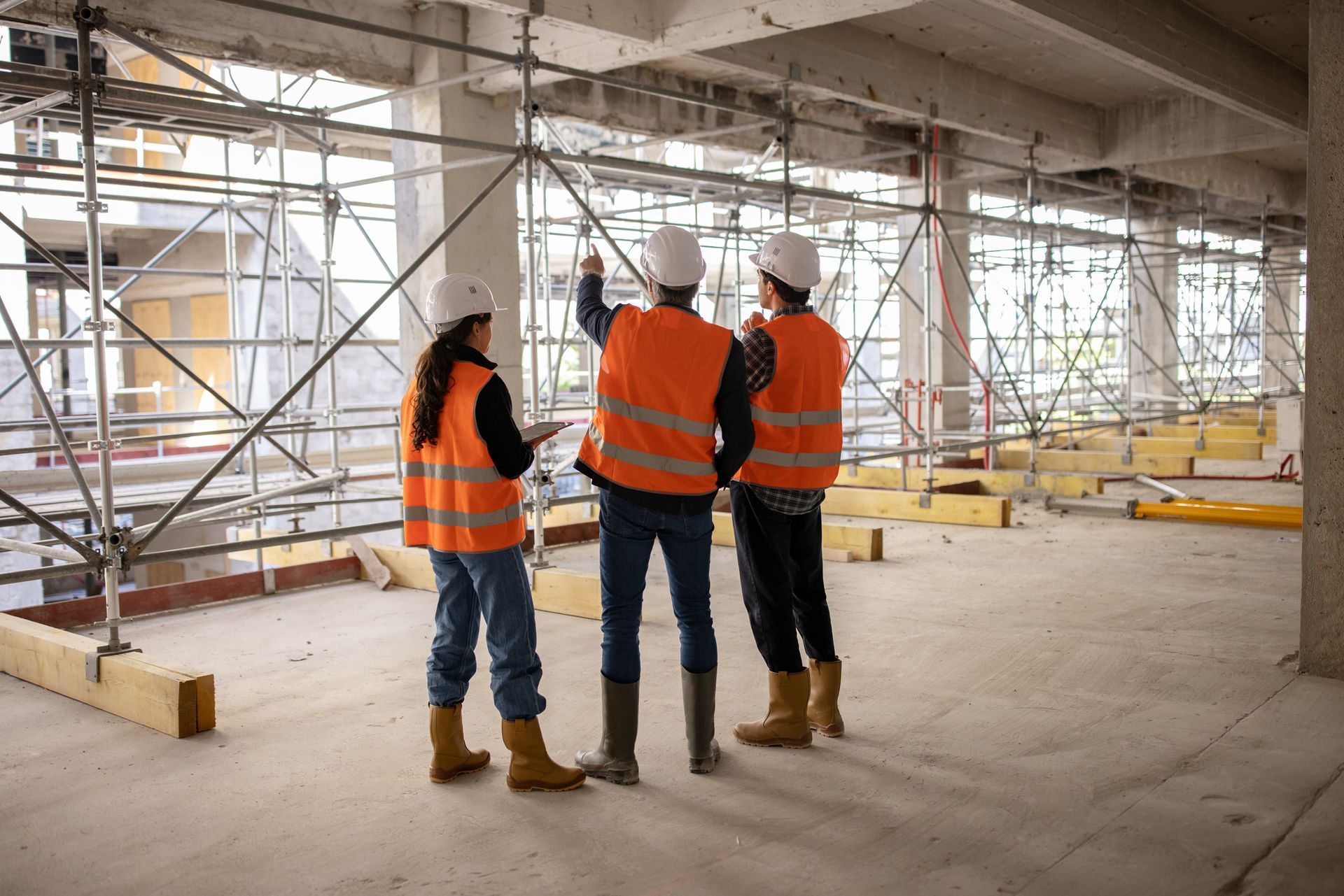 A group of construction workers are standing in a building under construction.