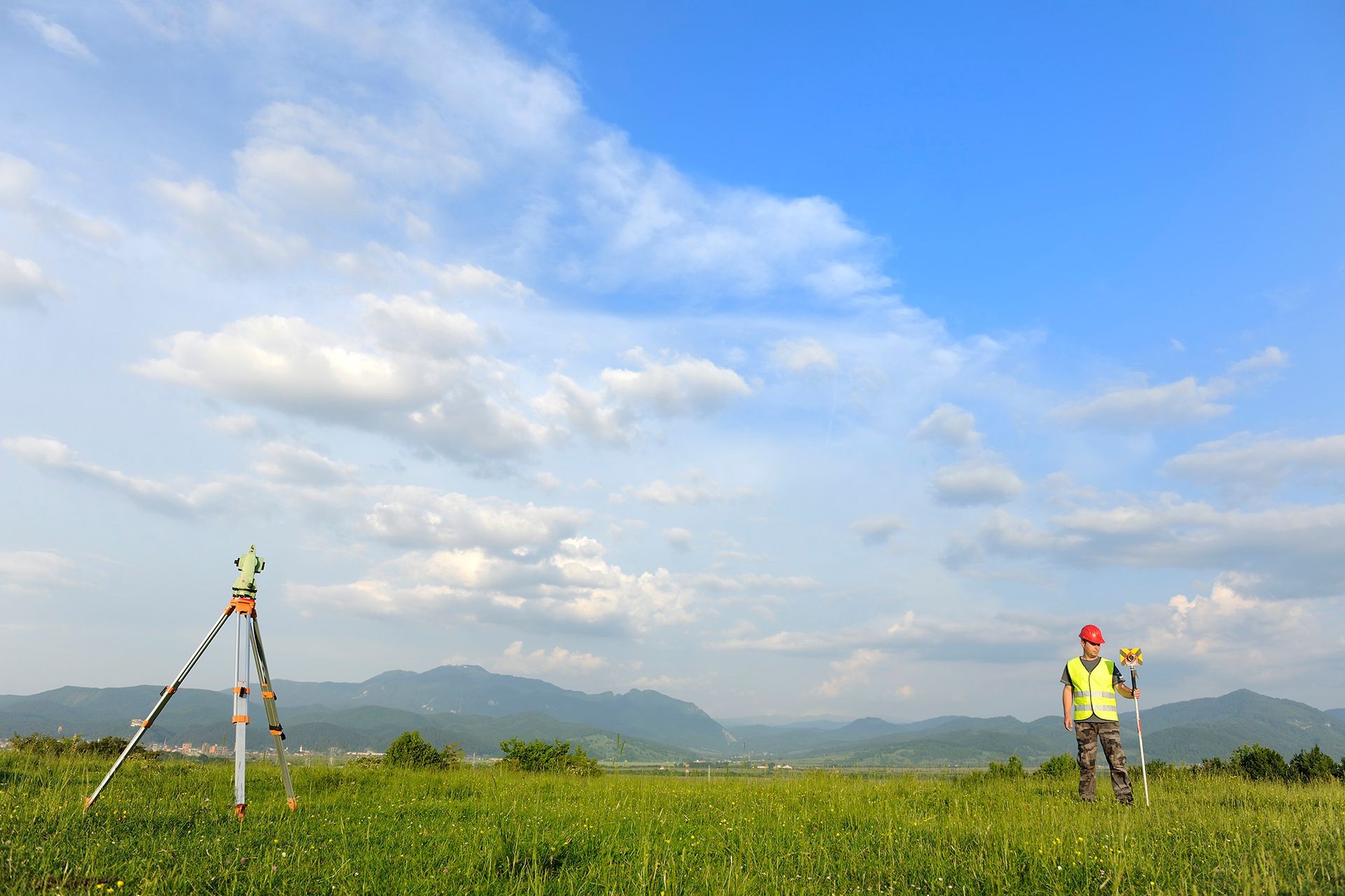 A man is standing in a field with a tripod in the background.