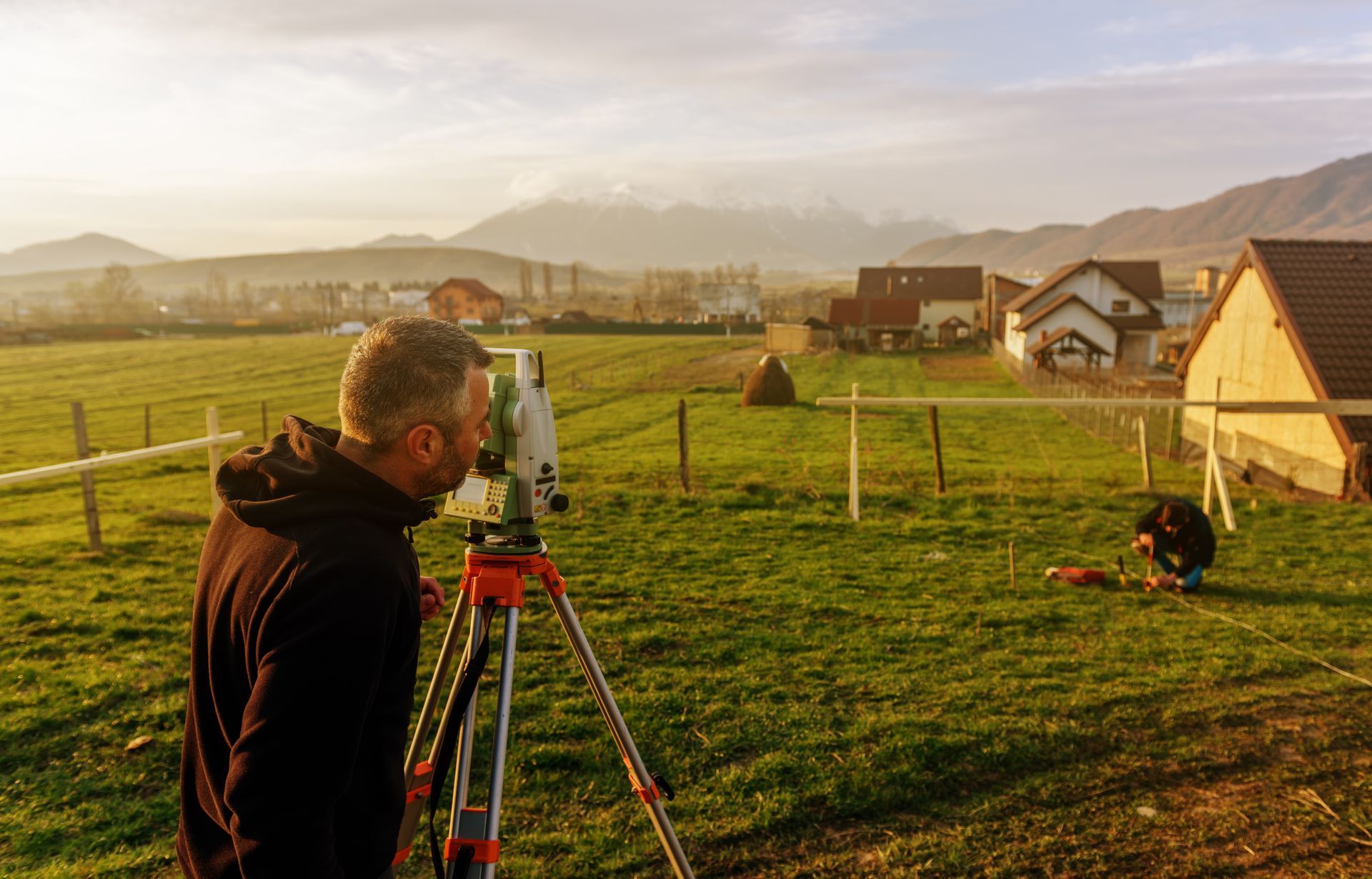 A man is standing in a field looking through a telescope.