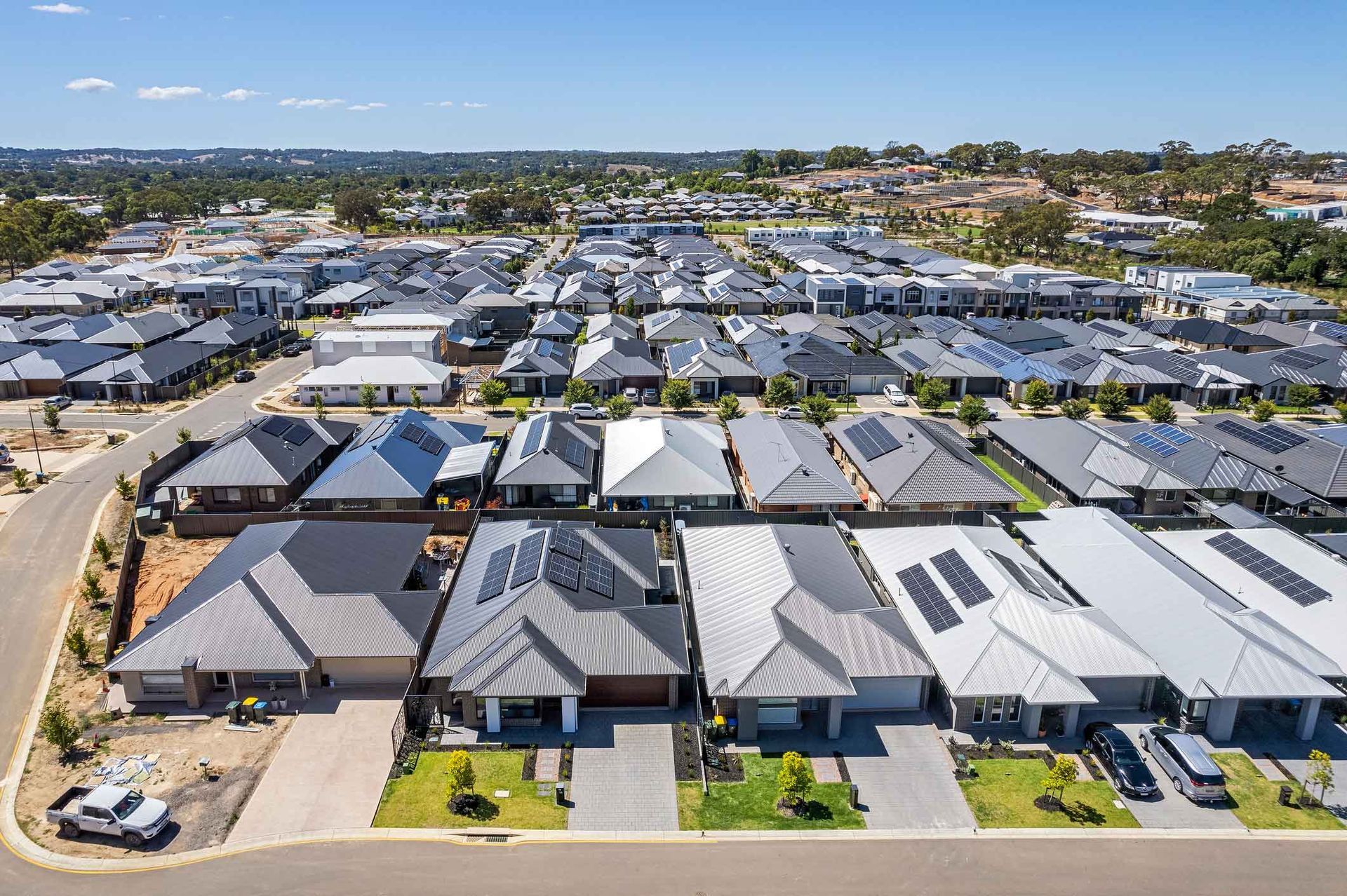 An aerial view of a residential area with lots of houses and solar panels on the roofs.