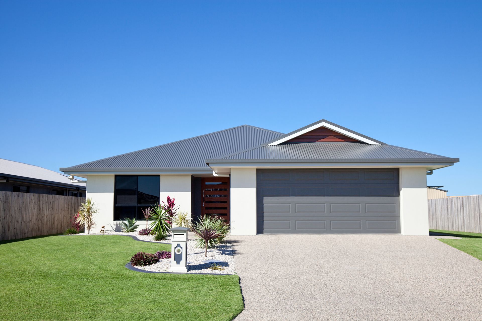 A white house with a gray garage door is sitting on top of a lush green lawn.