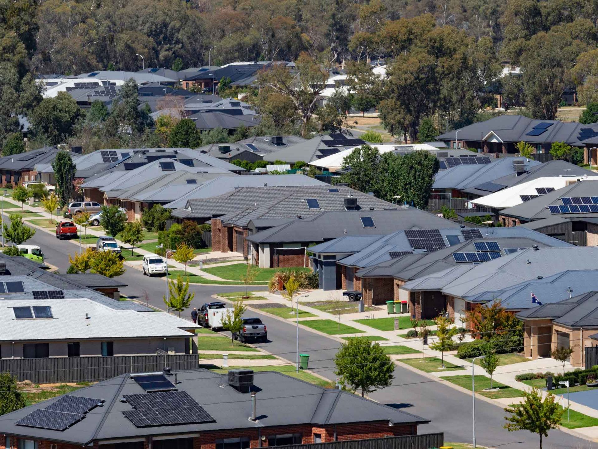 An aerial view of a residential area with lots of houses and solar panels on the roofs.