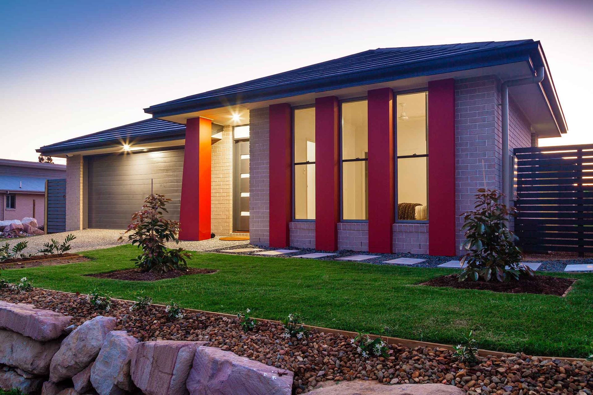 A house with red columns and a black garage door