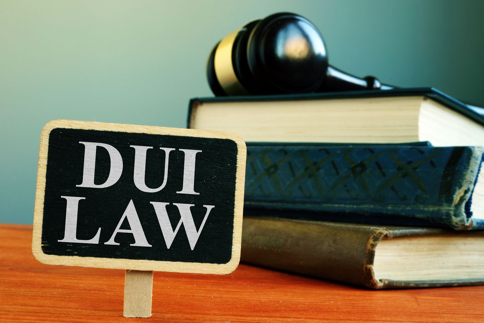 A DUI legal warning sign beside stacked law books with a judge’s gavel resting on top.
