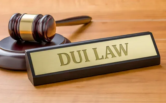 Close-up of a wooden gavel next to a nameplate reading “DUI Law” on a judge’s desk.