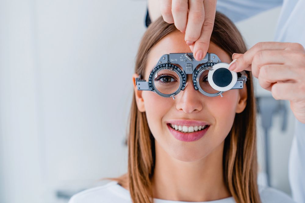 Examen ocular con foróptero a un paciente sonriente en una clínica.