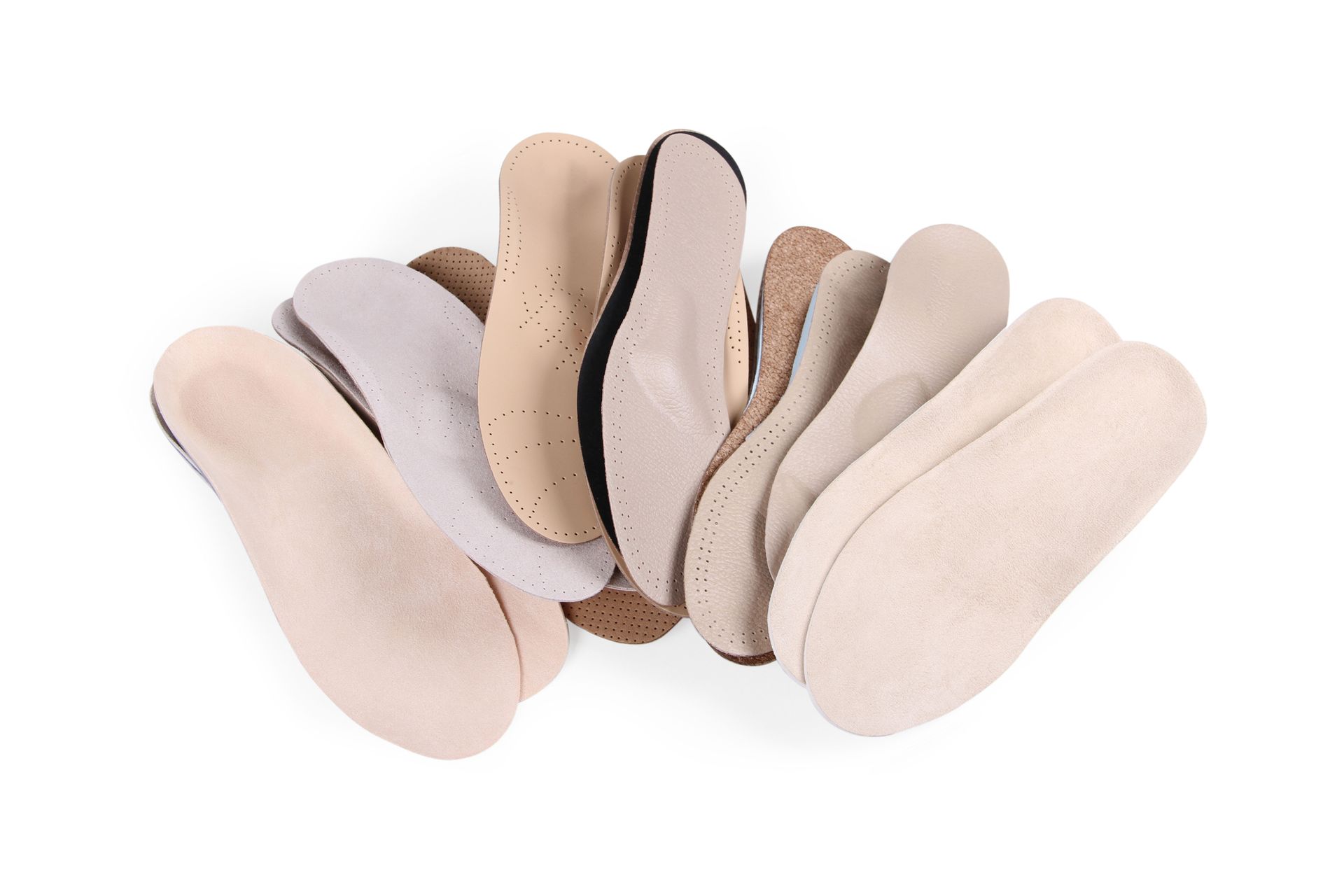 Plantillas de zapatos sin cordones de color beige y crema surtidas, dispuestas en forma de abanico sobre un fondo blanco.
