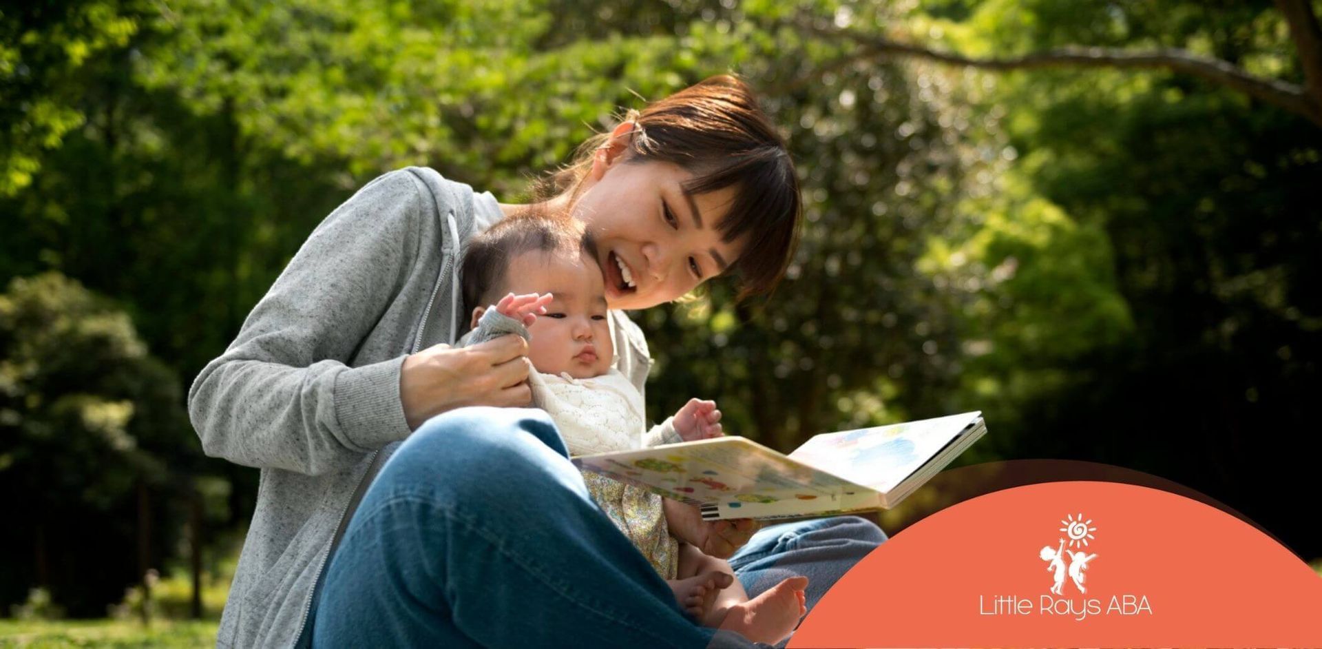 ABA therapist reading a picture book to a baby with autism in a park.