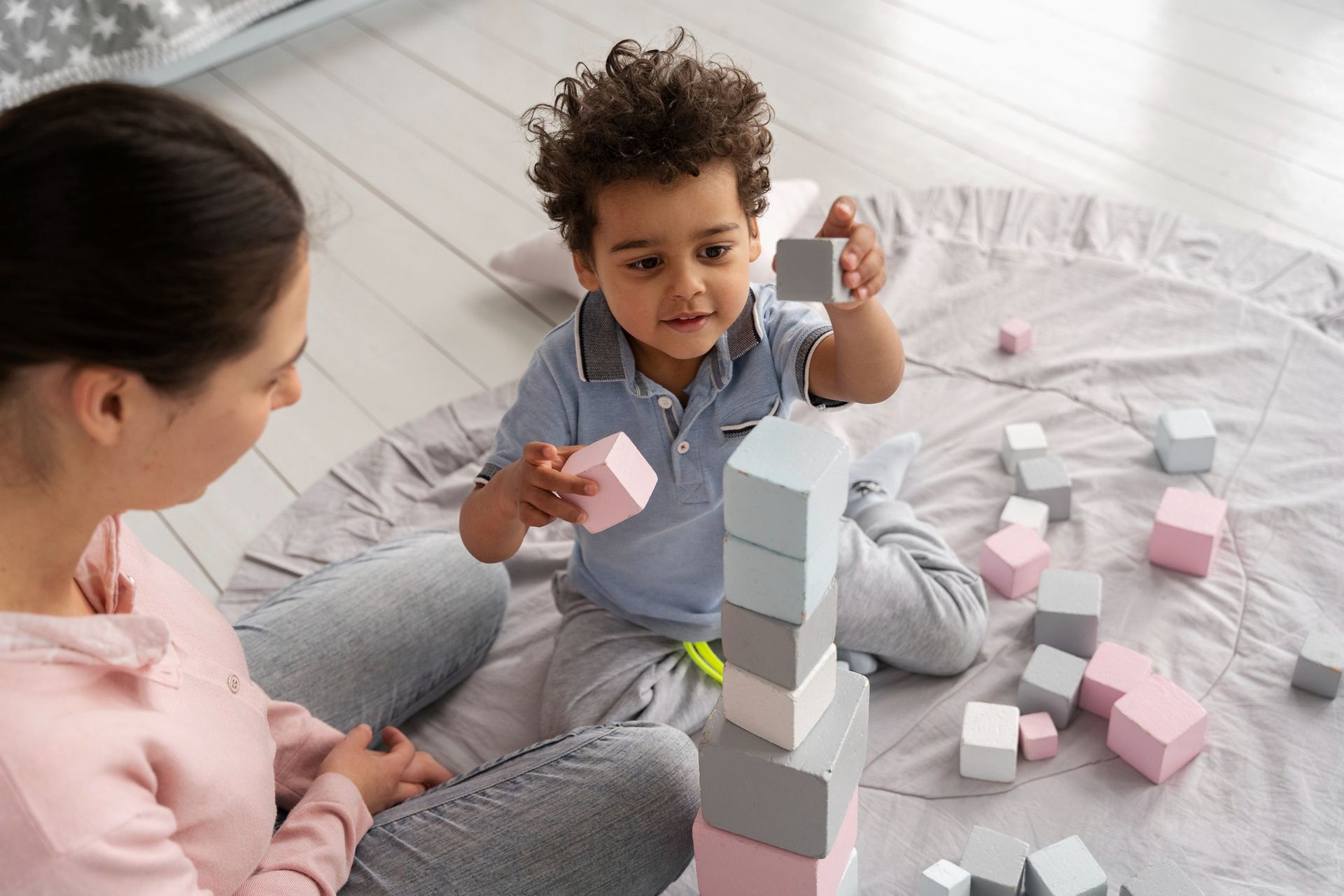 An RBT and a child are playing with blocks on the floor during an in-home aba therapy session