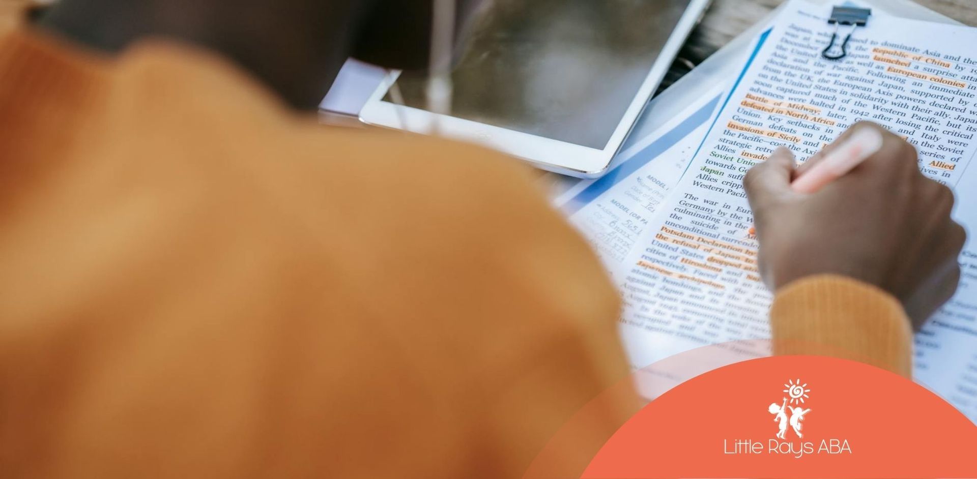 BCBA student highlighting text in orange while studying for BCBA exam with laptop beside in Florida