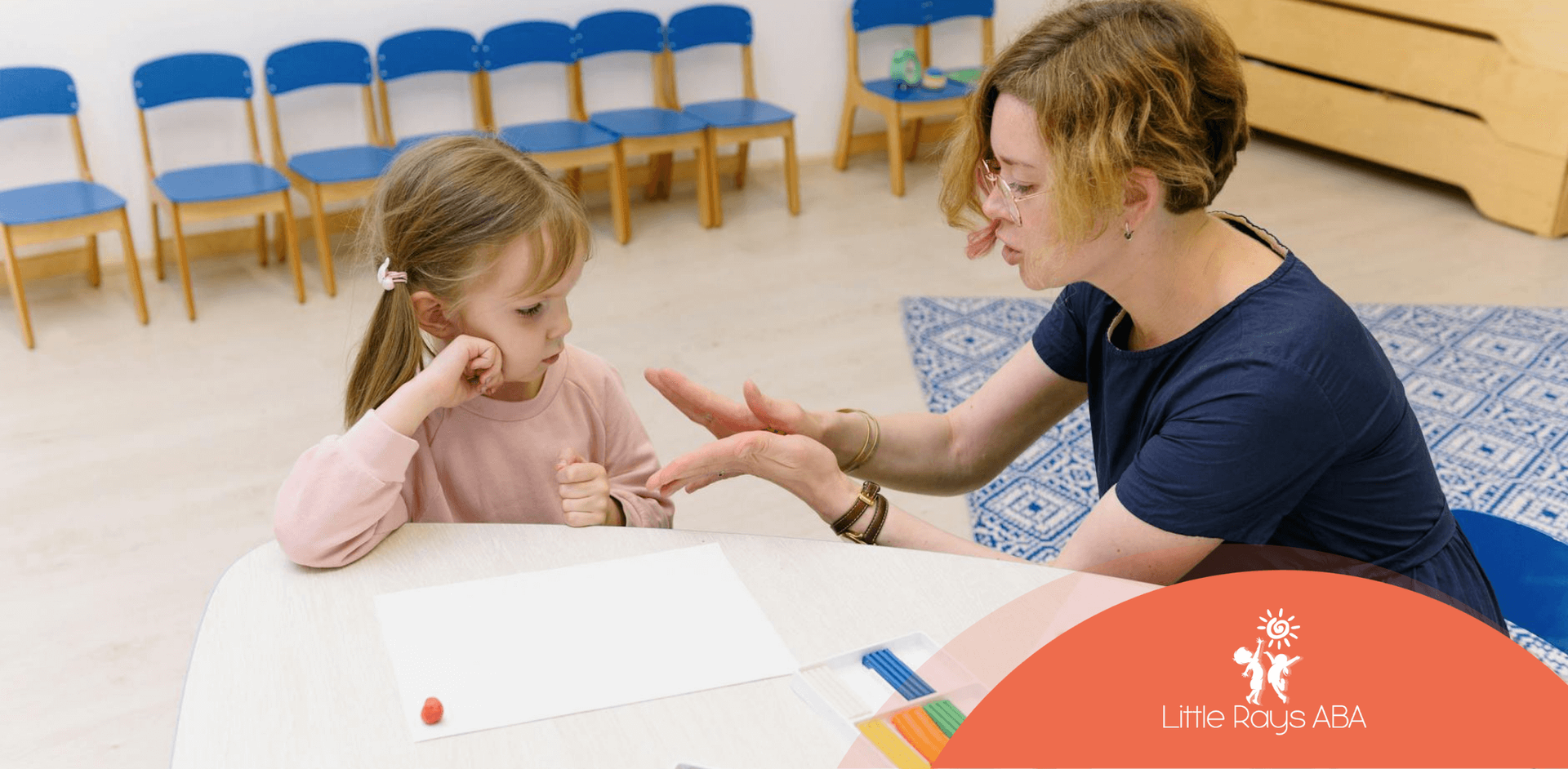 A BCBA and a young autistic child interacting during a lesson with colorful materials, part of BIP.