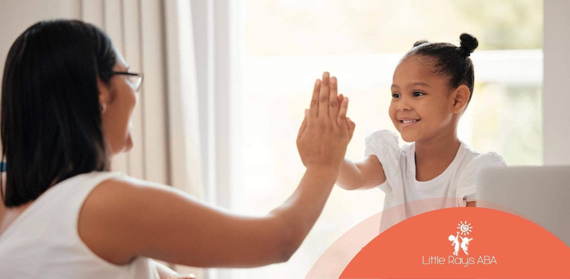 A BCBA and a little girl are giving each other a high five in ABA therapy.
