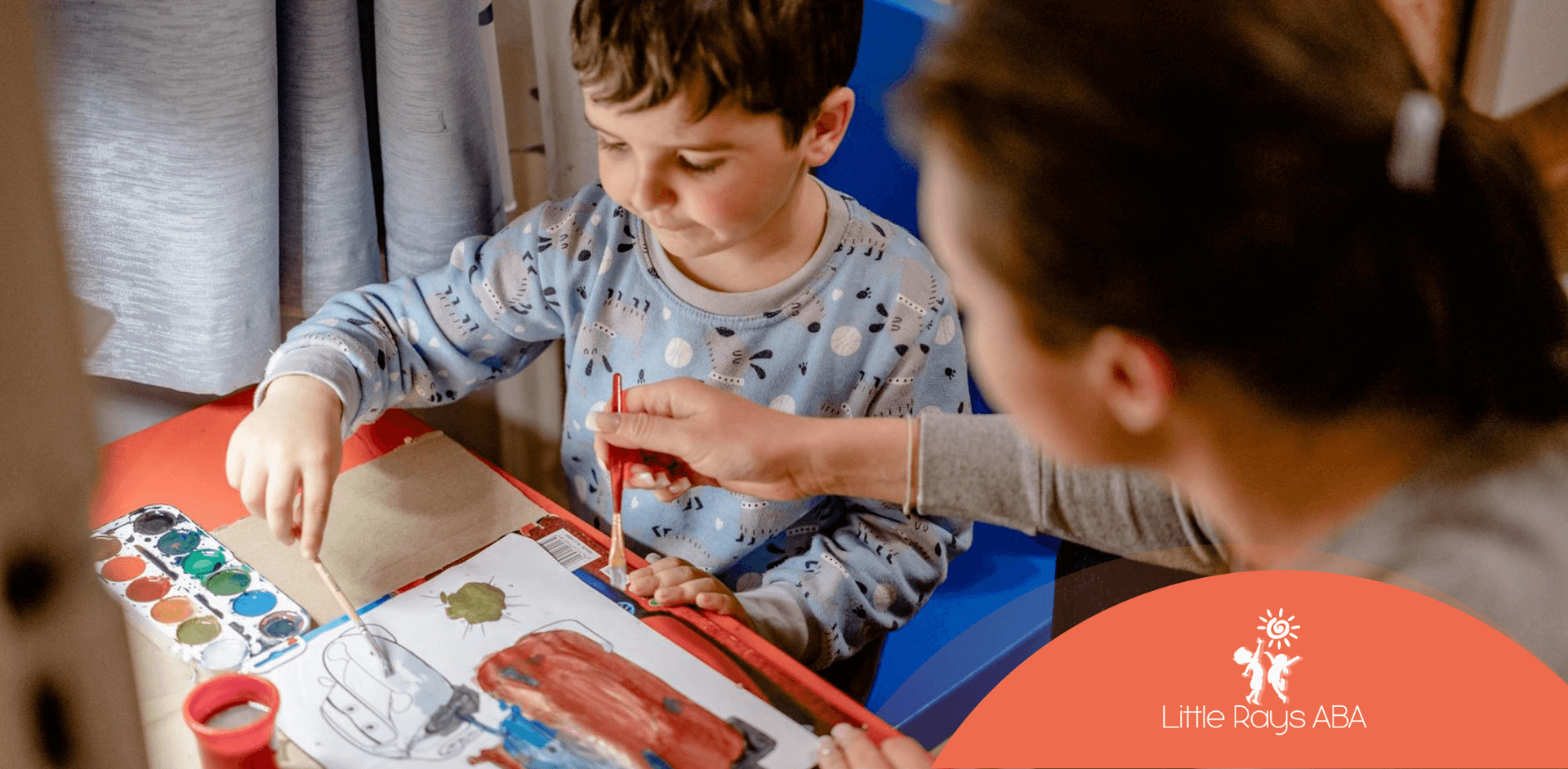 An autistic child painting with help from an RBT at a table during in-home ABA therapy in Florida.