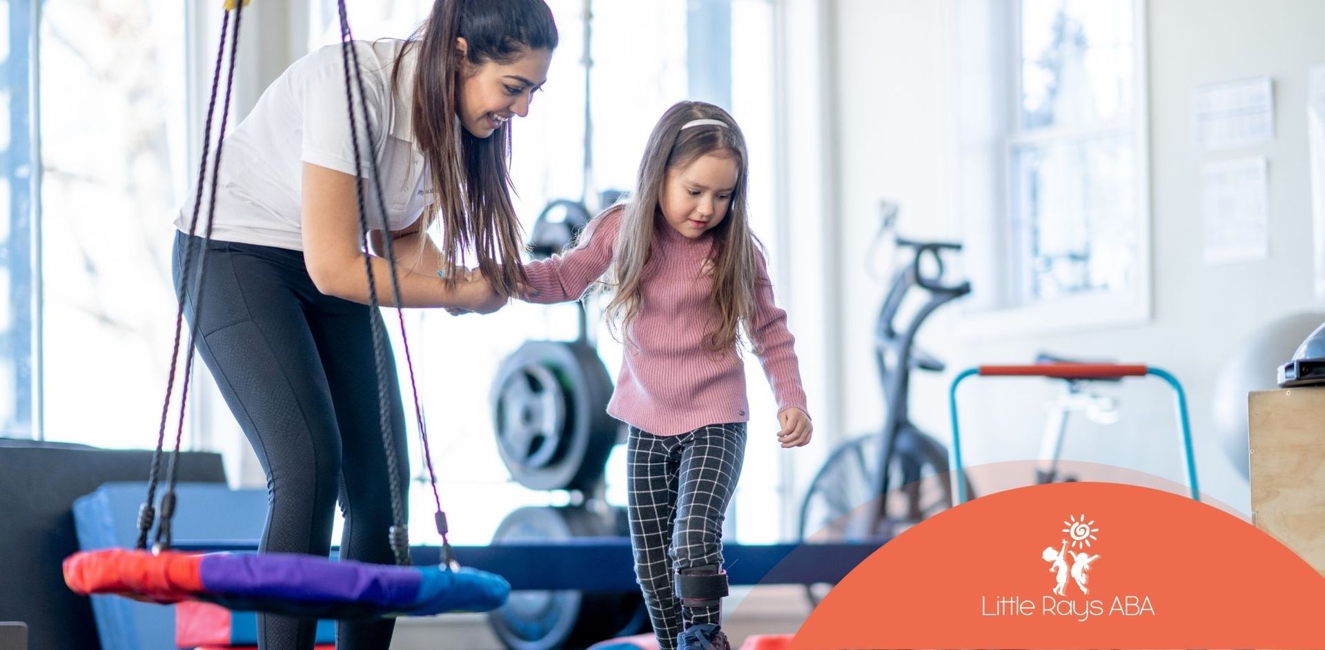 A woman is helping a little girl balance on a balance beam.