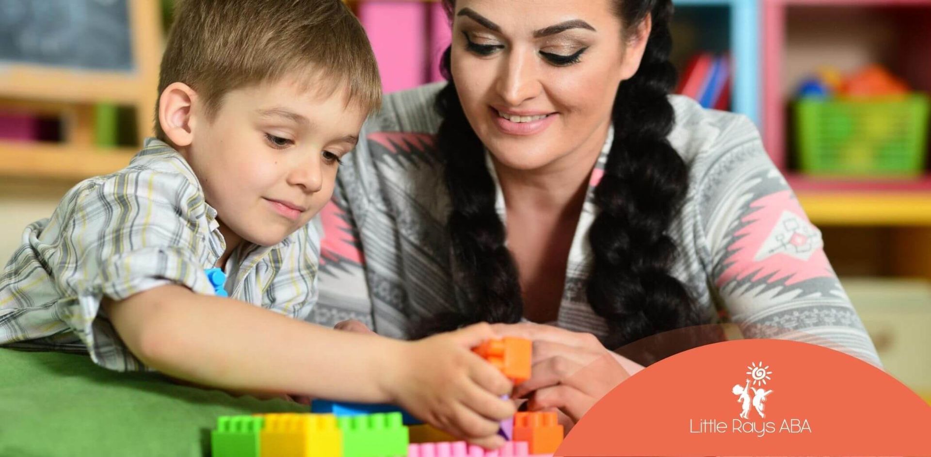 Child building colorful blocks with ABA therapist's support.