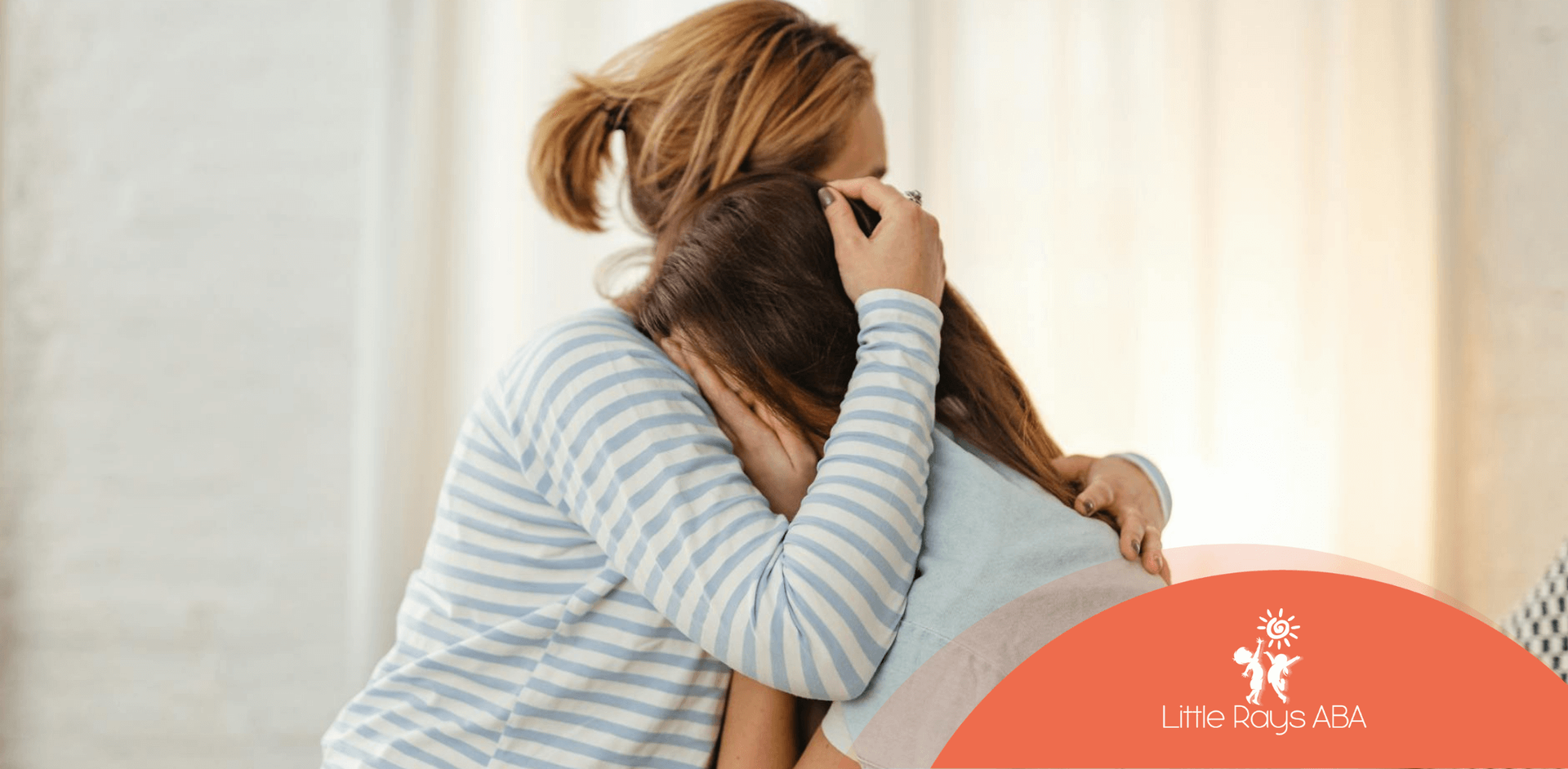 ABA therapist comforting the mother of an autistic child, both sitting together and hugging in FL.