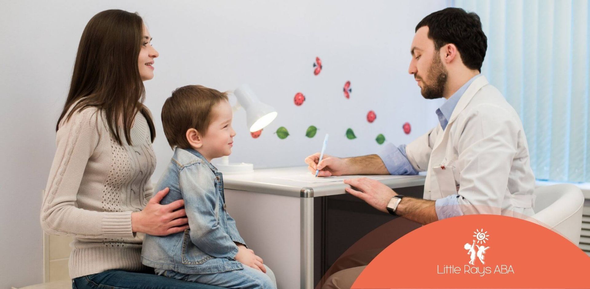 A woman is holding a child while a doctor talks to them.