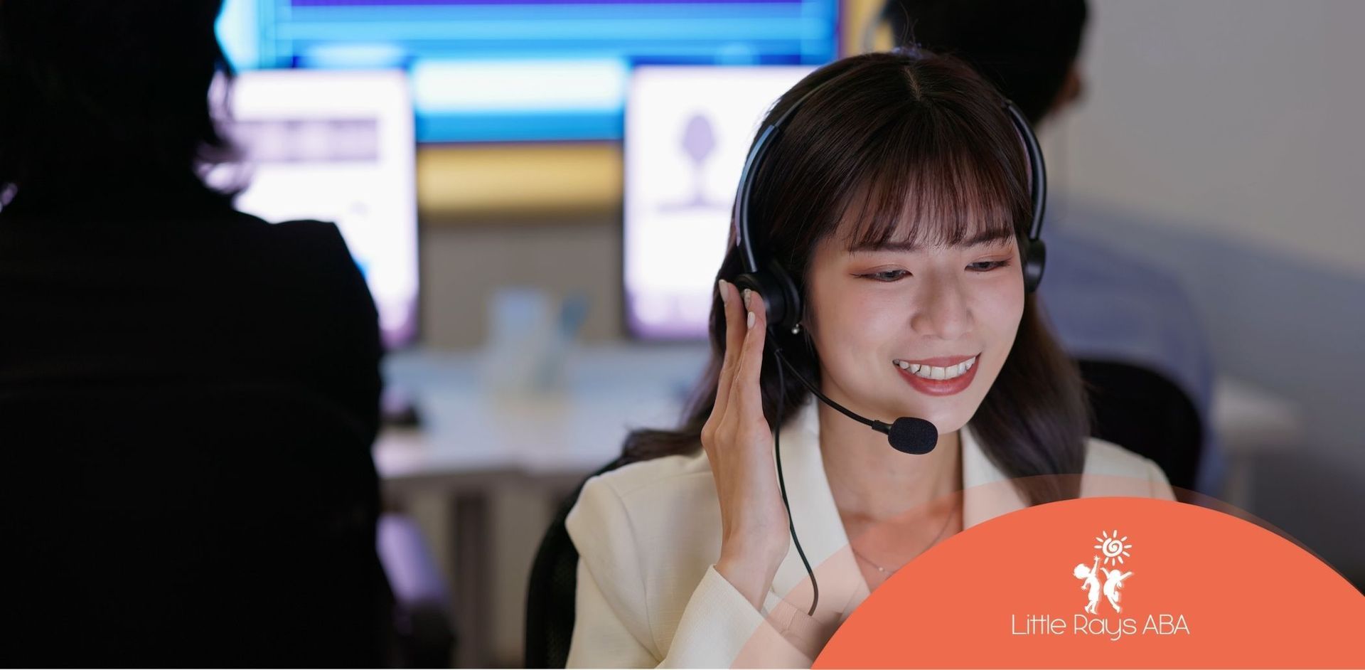 A woman wearing a headset is sitting in front of a computer.
