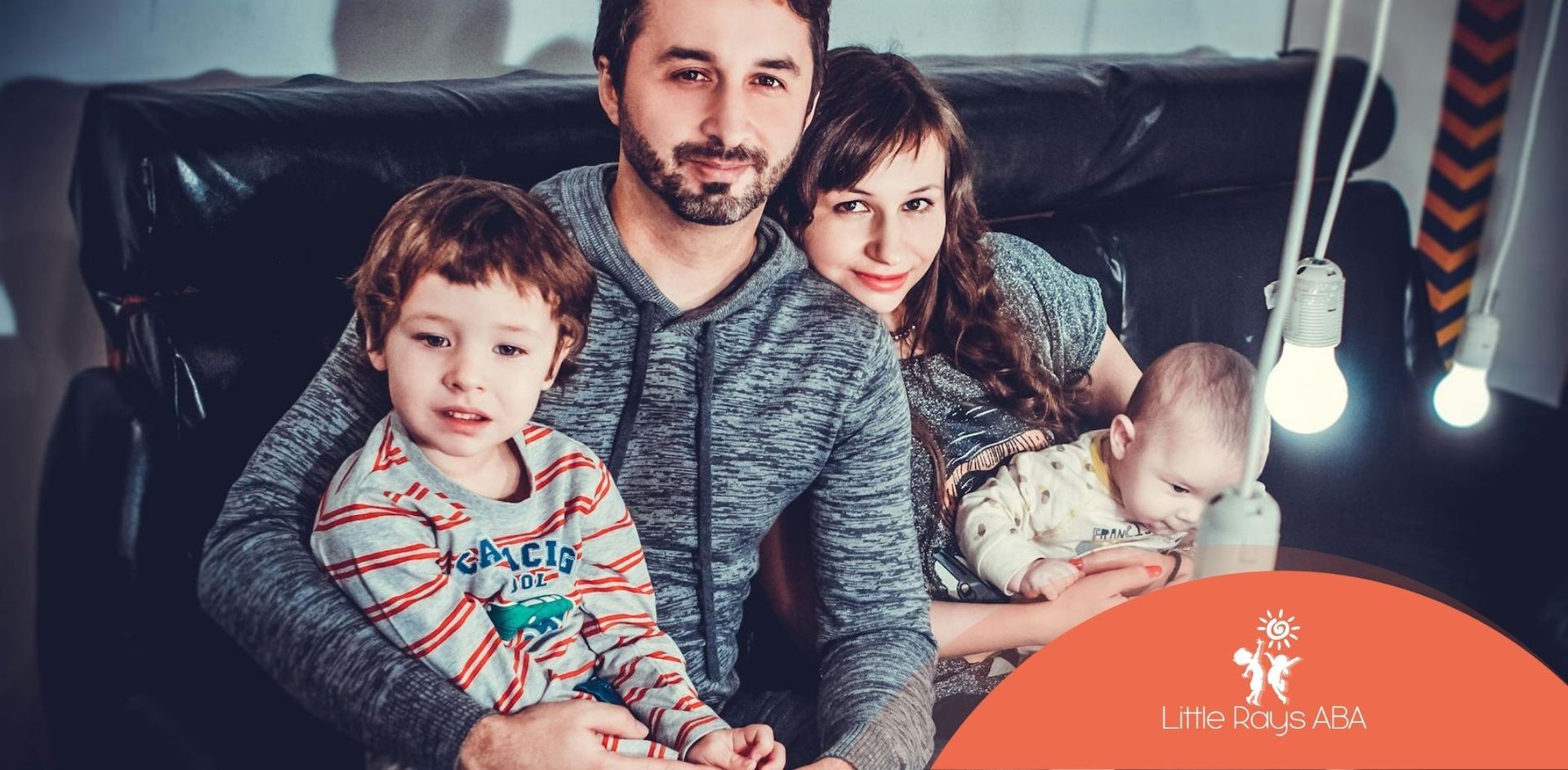 Family on couch holding autistic children with light bulbs hanging around them at home in Florida.