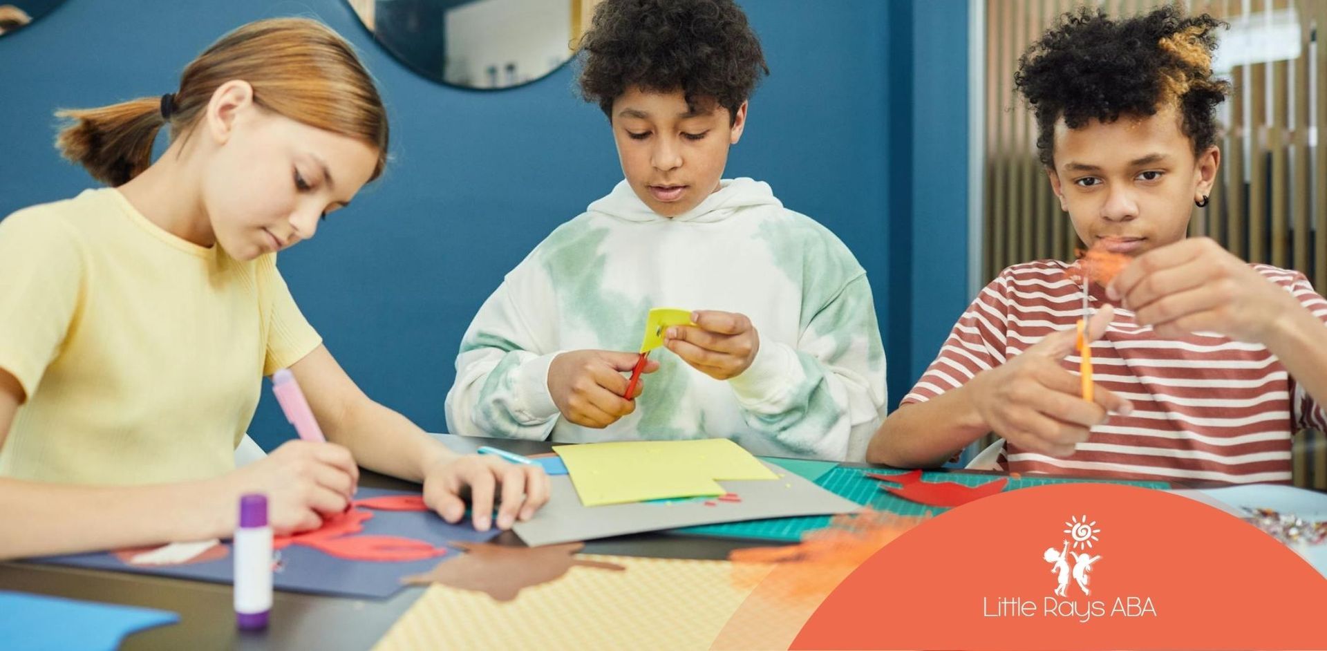 Three autistic kids focused on arts and crafts at a classroom table during ABA therapy in Florida.