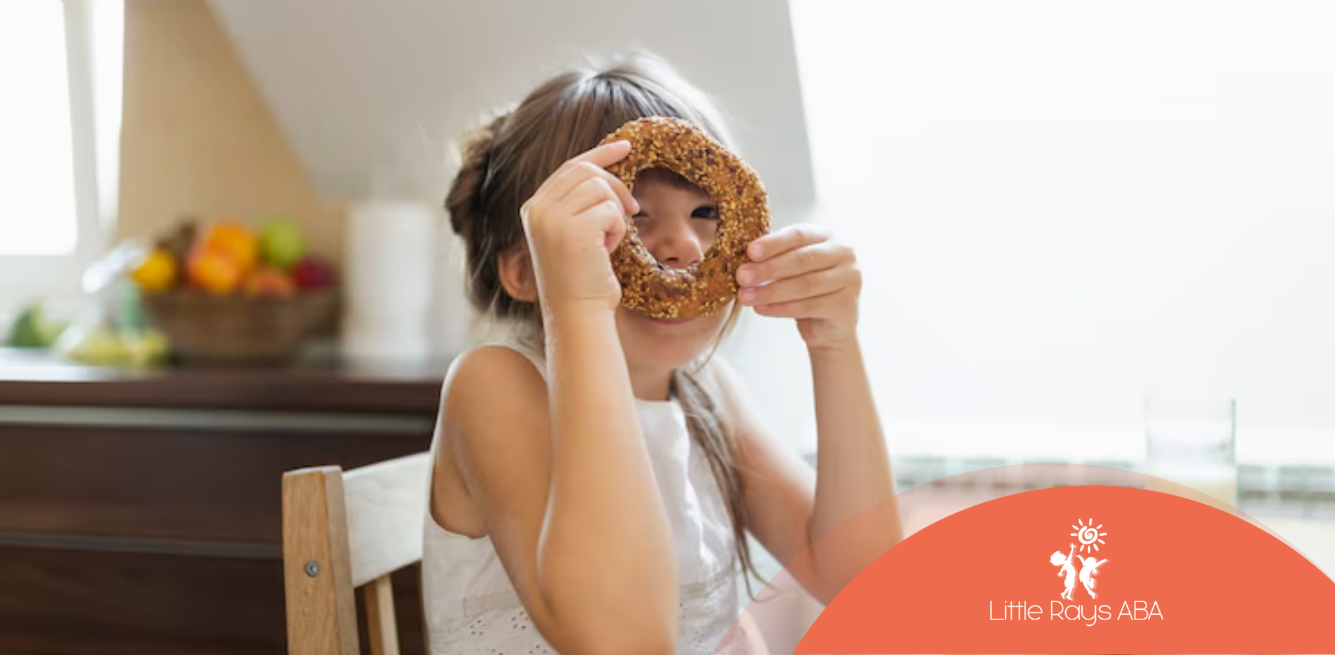 A little girl is sitting at a table eating a pretzel.