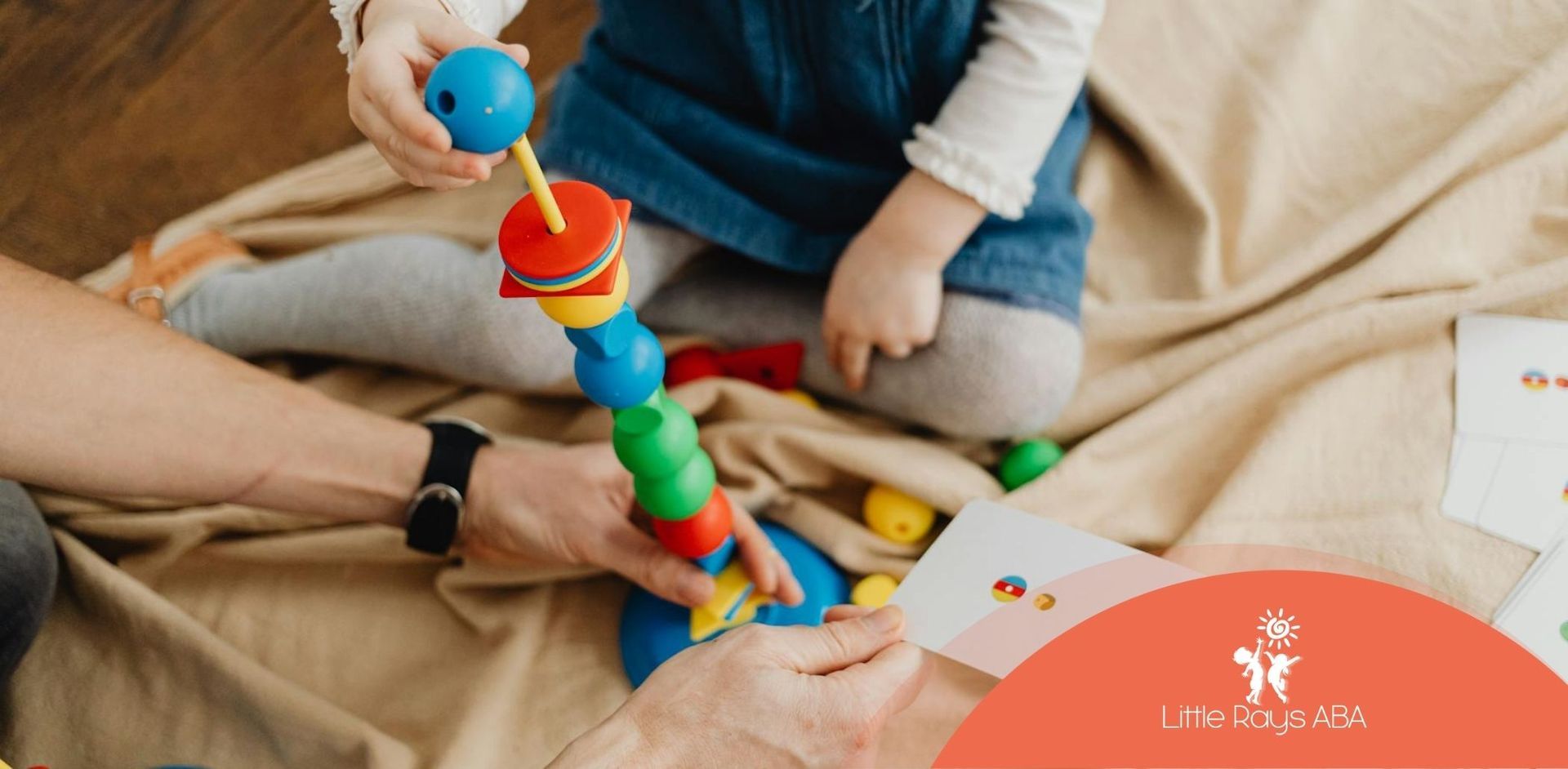 An autistic child stacking colorful toy pieces while ABA therapist holds a flashcard in Florida.