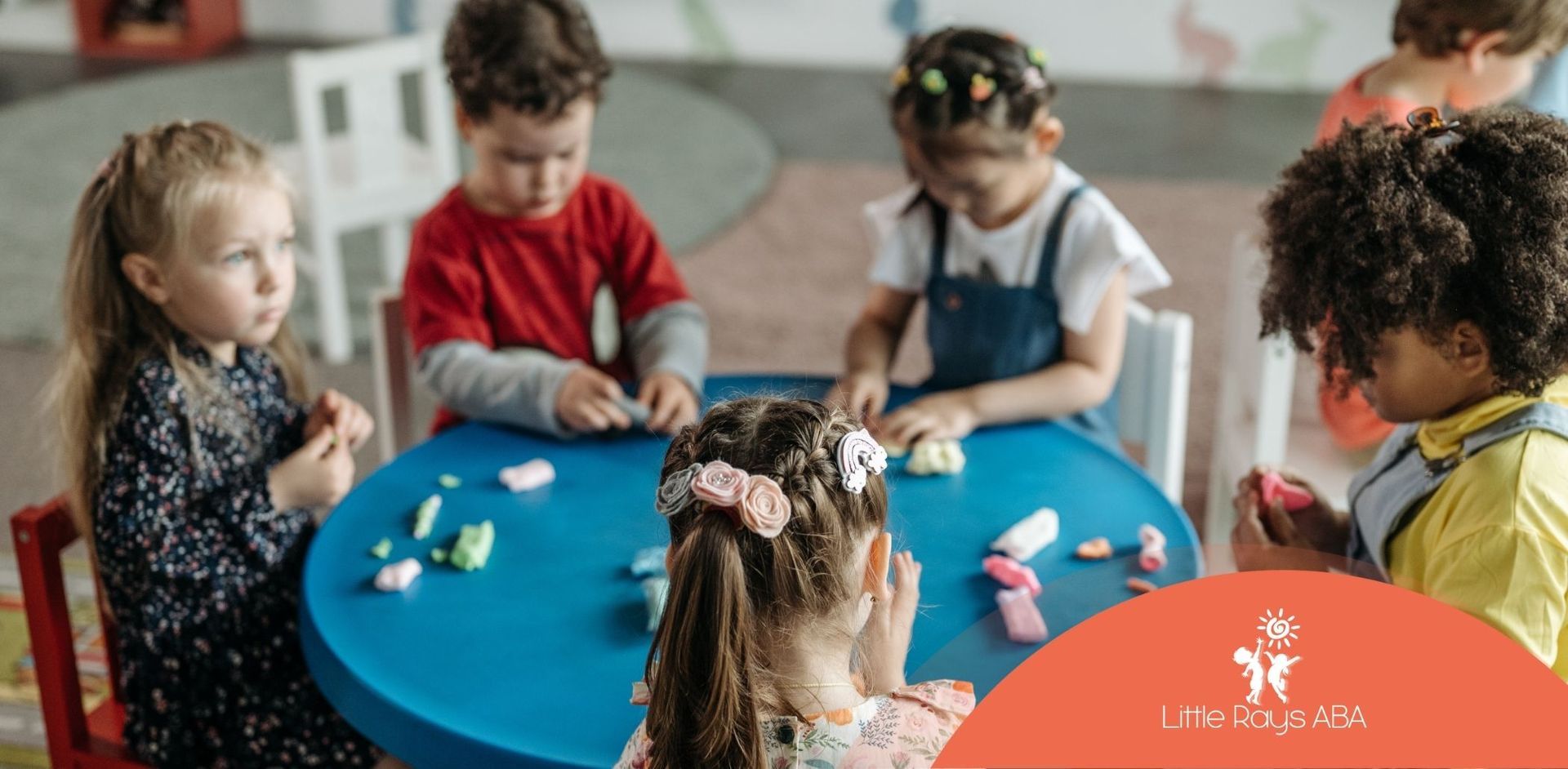 A group of children are sitting at a table playing with play dough.