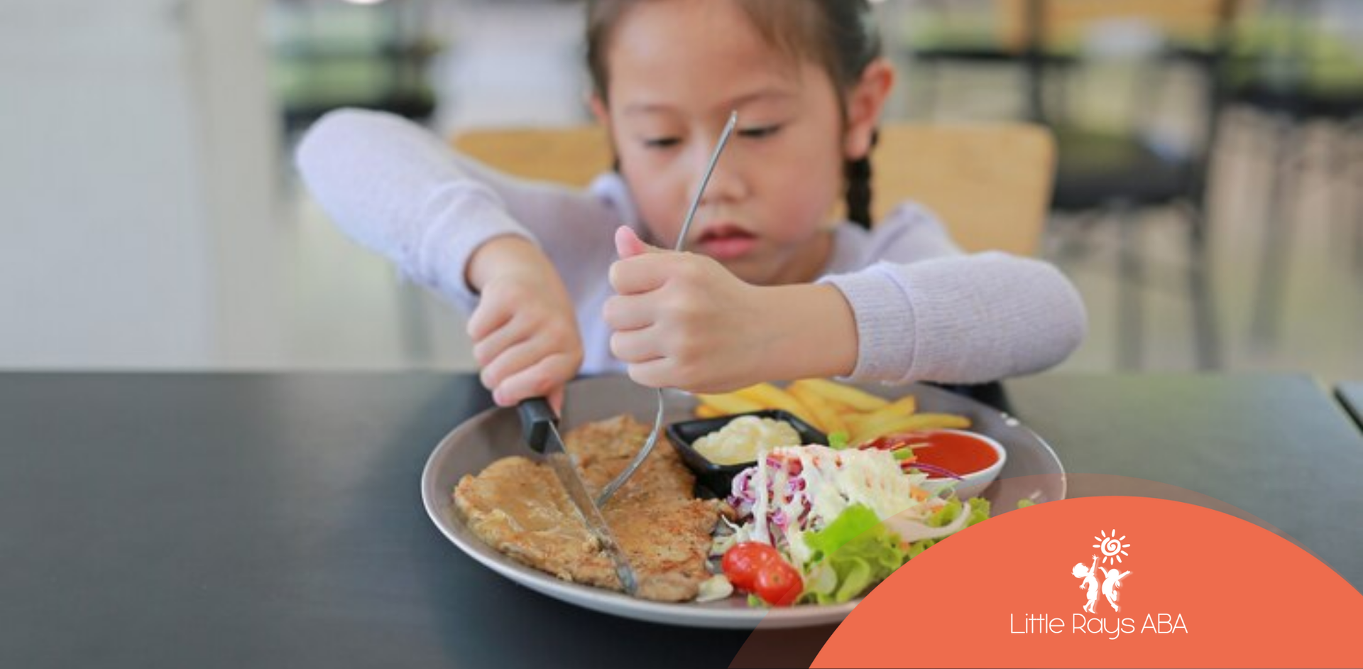 A little girl is sitting at a table eating a plate of food.