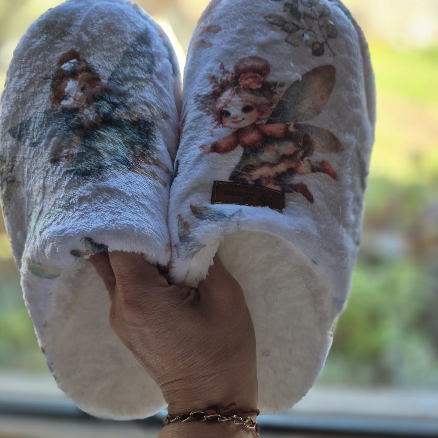 Un par de zapatillas de color azul claro con estampado floral, vistas de frente sobre un escalón de madera.