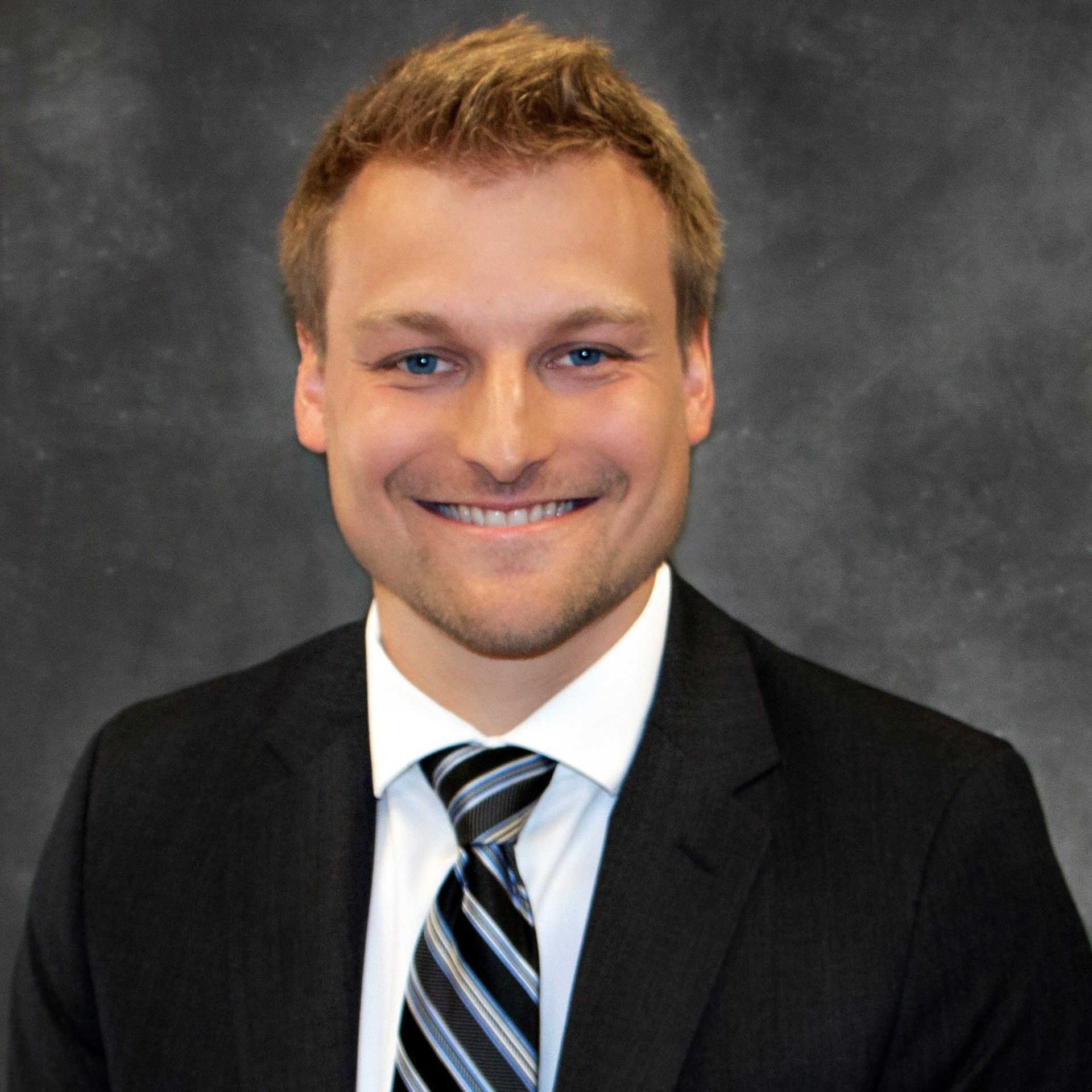 A man in a suit and tie is smiling for the camera