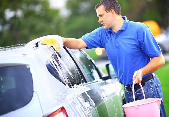 A Man Is Washing A Car With A Sponge While Holding A Pink Bucket - San Pablo, CA - Grand Prix Car Wash San Pablo