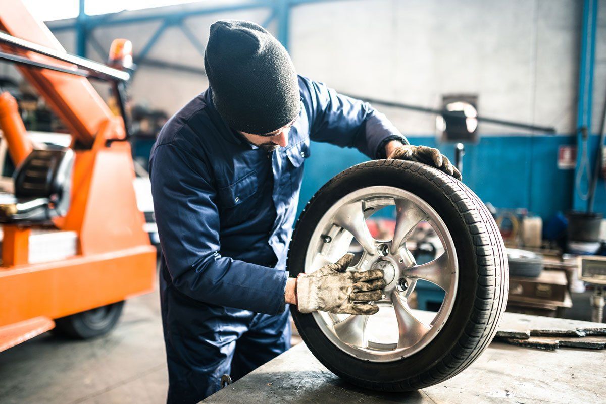 A Man Is Changing A Tire In A Garage - San Pablo, CA - Grand Prix Car Wash San Pablo