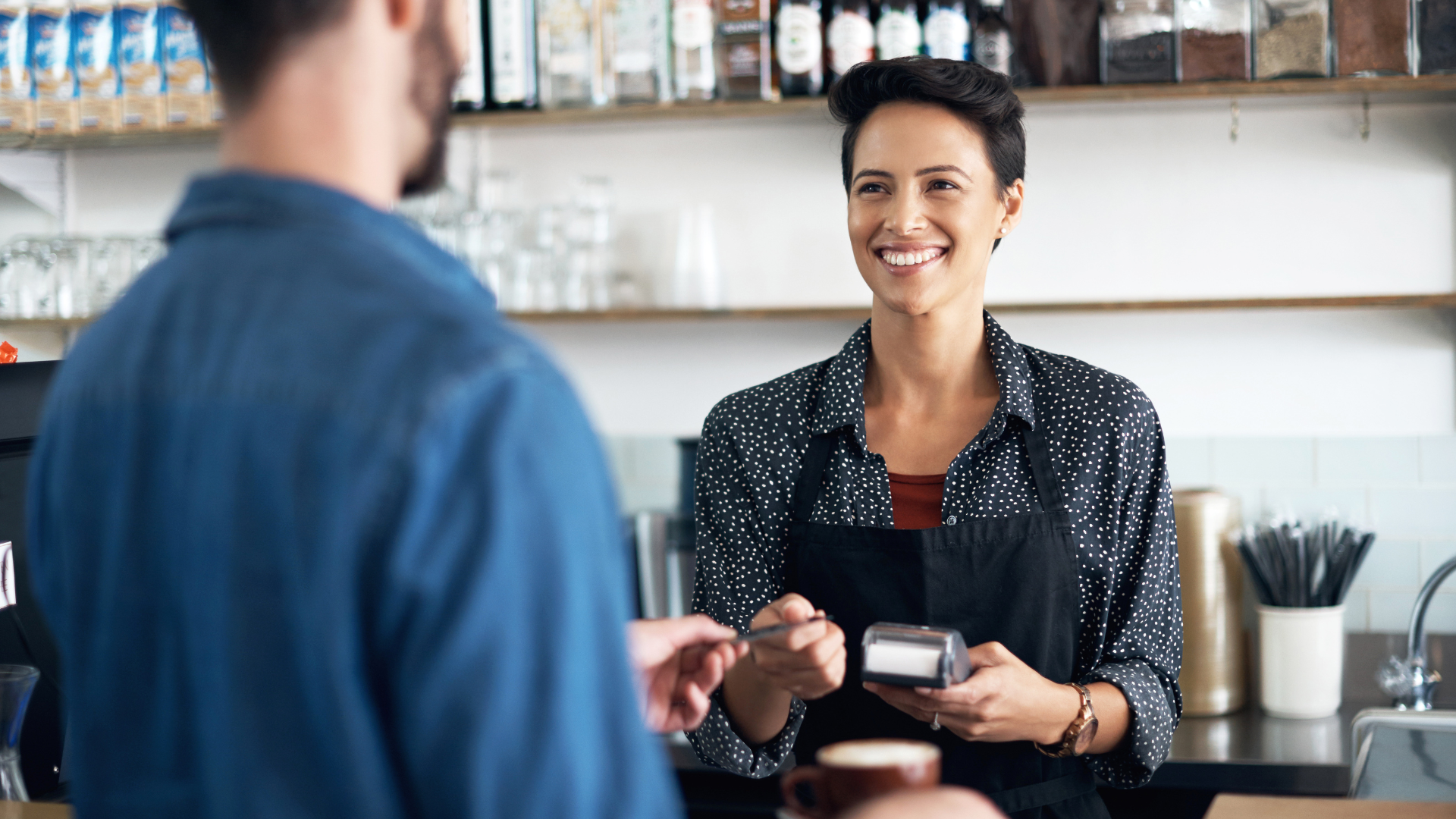 A man is paying for a cup of coffee with a credit card.