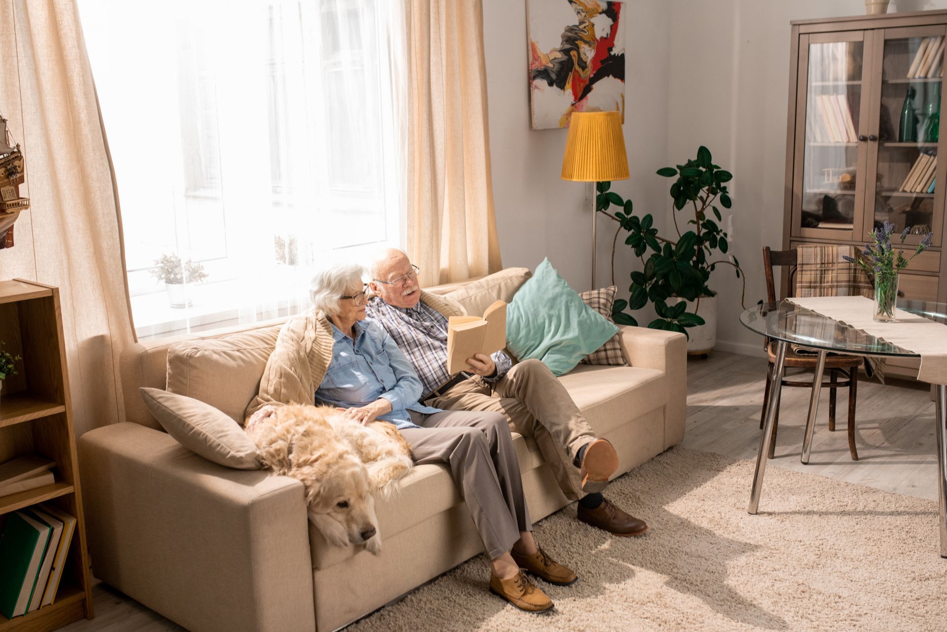 an elderly couple is sitting on a couch with a dog