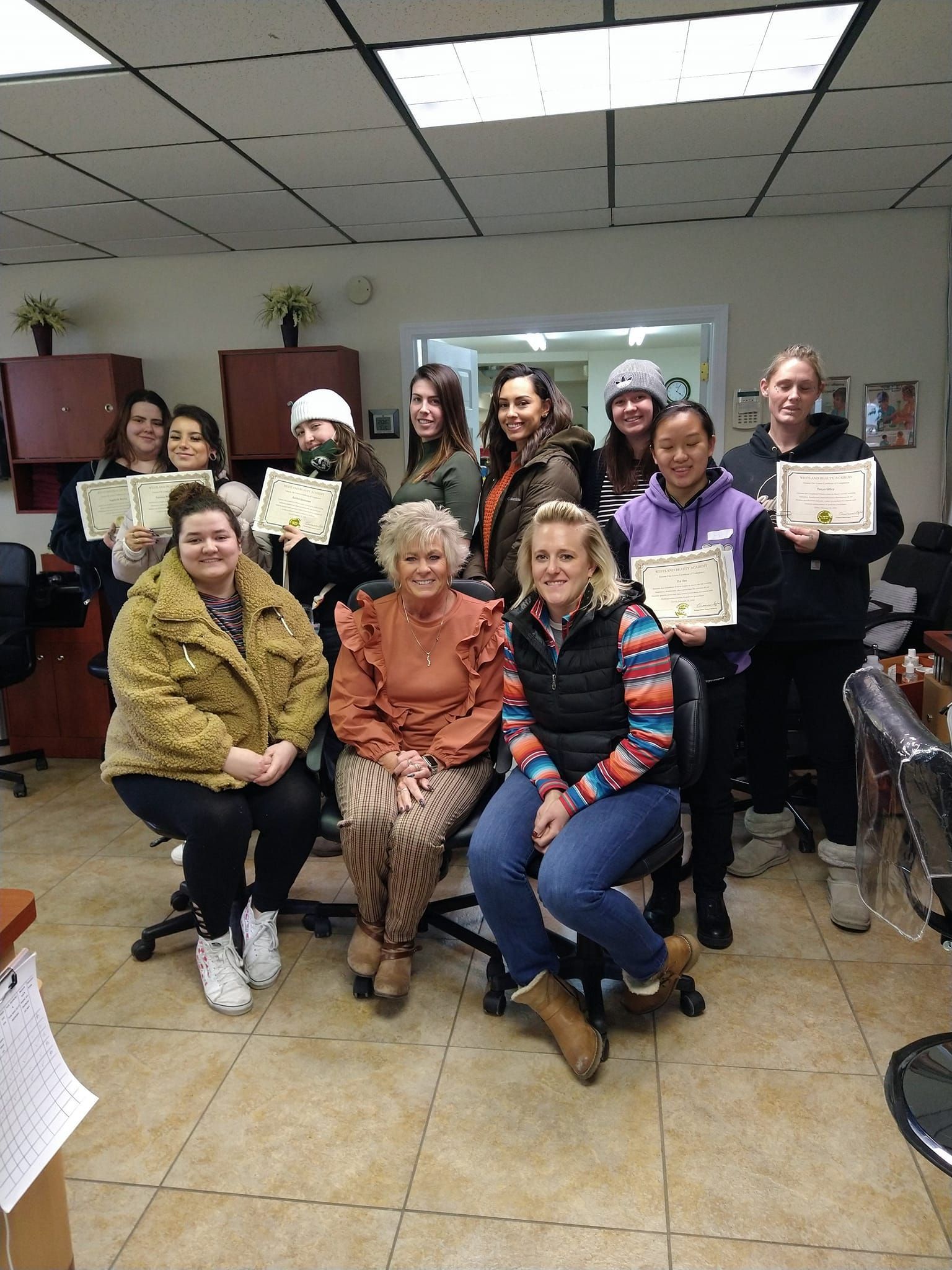A group of women are posing for a picture in a room while holding certificates.