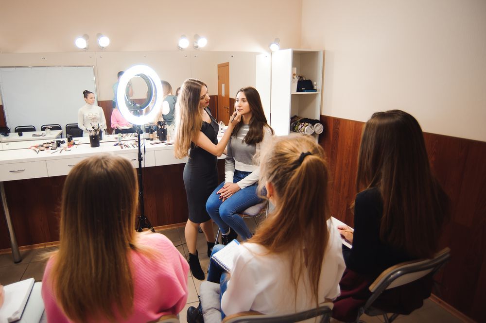 A group of women are sitting in a room getting their makeup done.