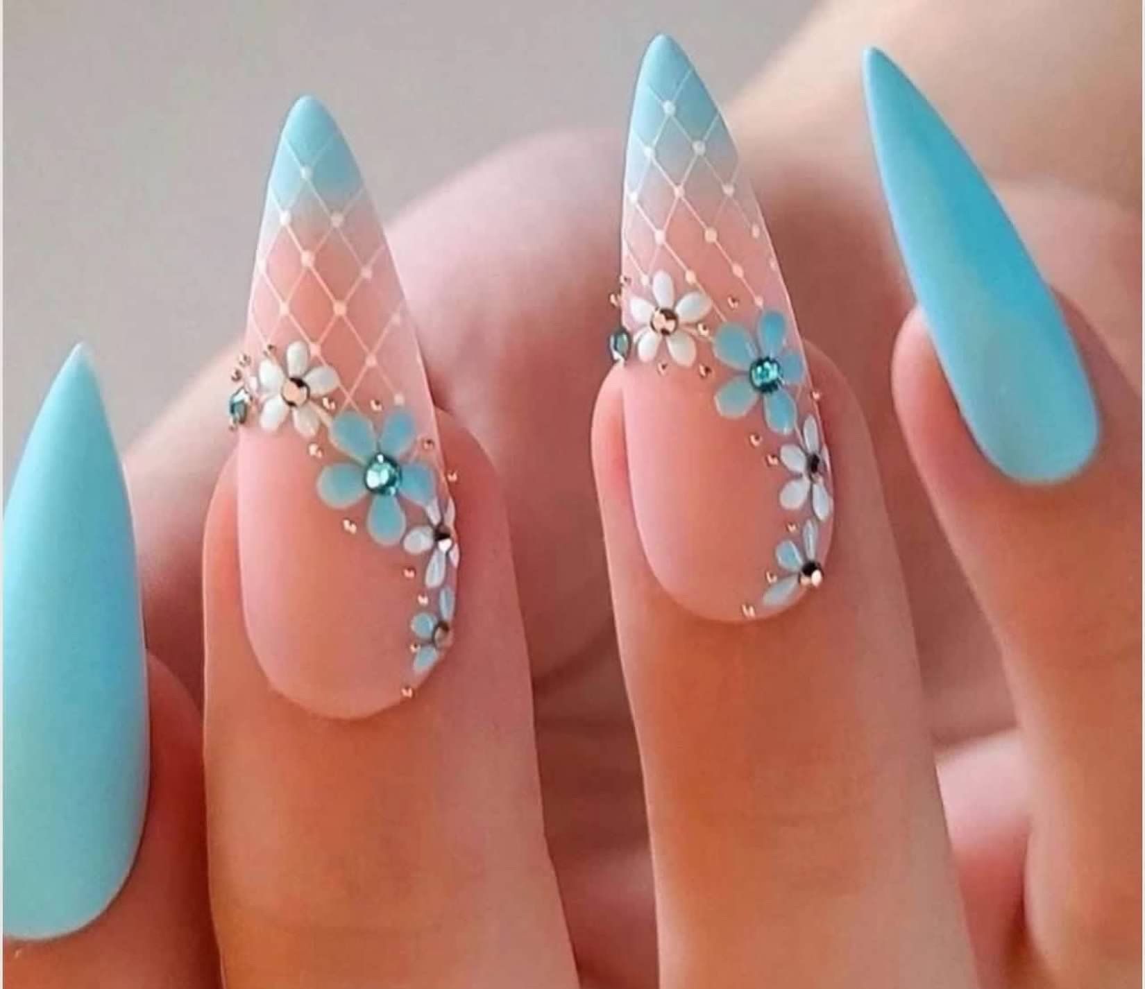 Close-up of manicured nails with a light blue and peach design featuring a floral pattern and netting detail.