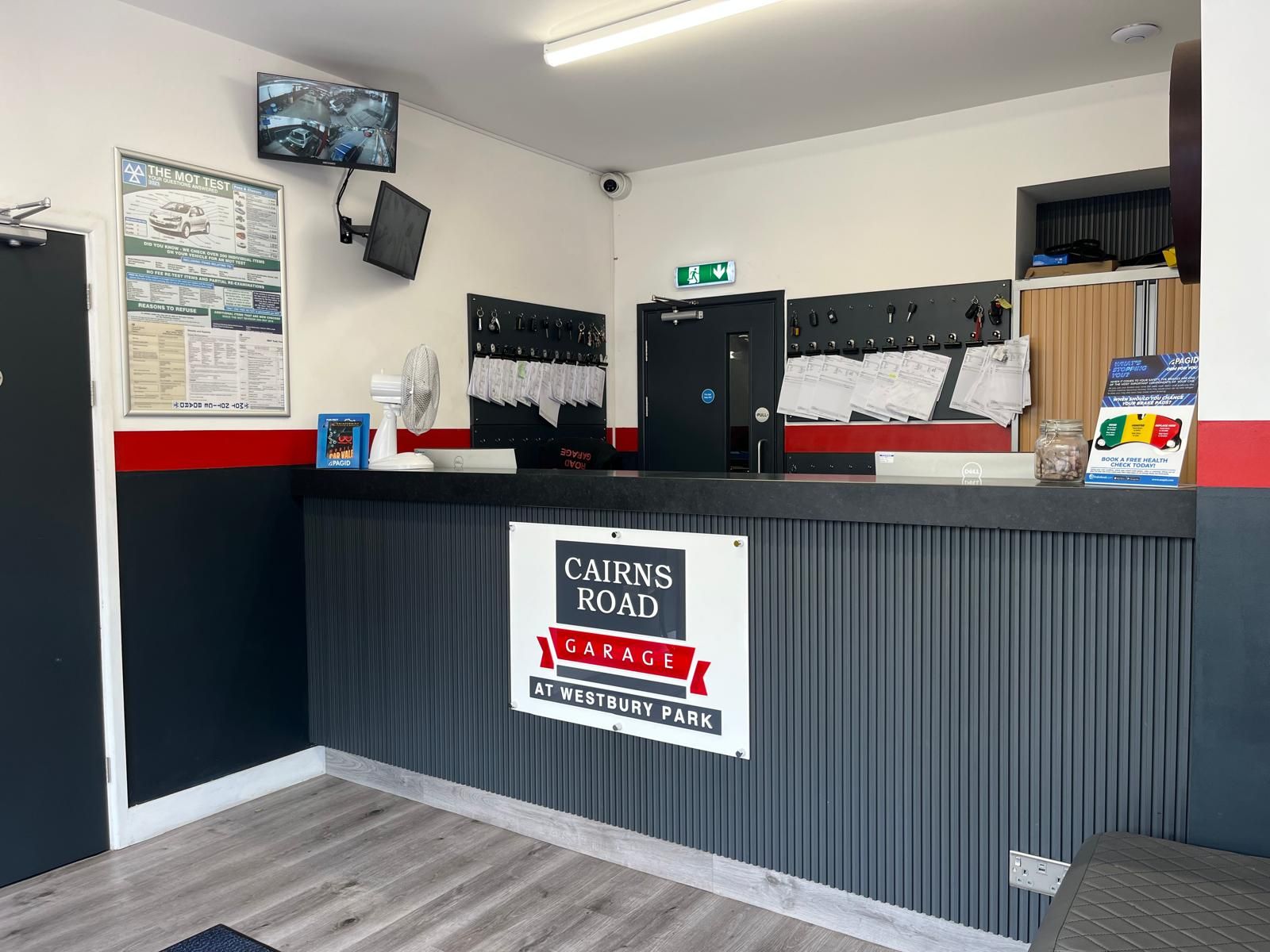 Reception area of Cairns Road Garage with a counter, signage, and a TV screen.
