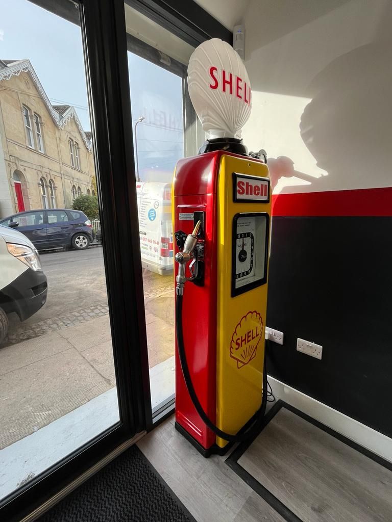 Shell gas pump, red and yellow, indoors near a window.