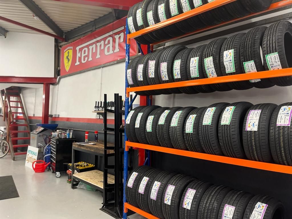 Tires on shelves in a garage with a Ferrari sign on the wall.