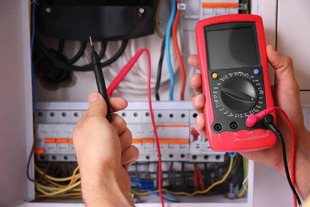 a person is holding a multimeter in front of an electrical box