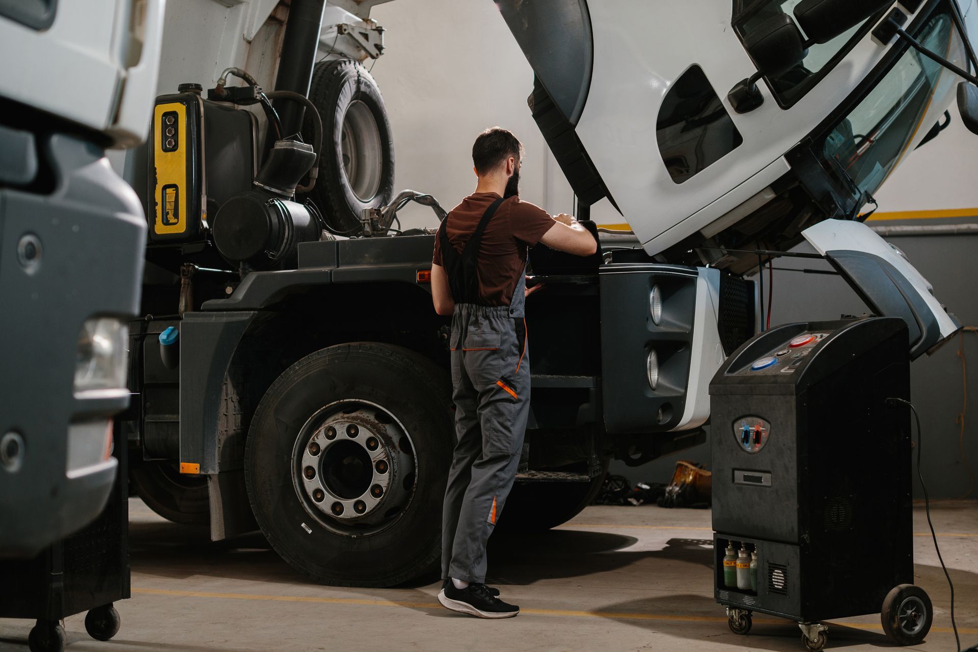 Mechanic working on a truck in a garage, using a machine.