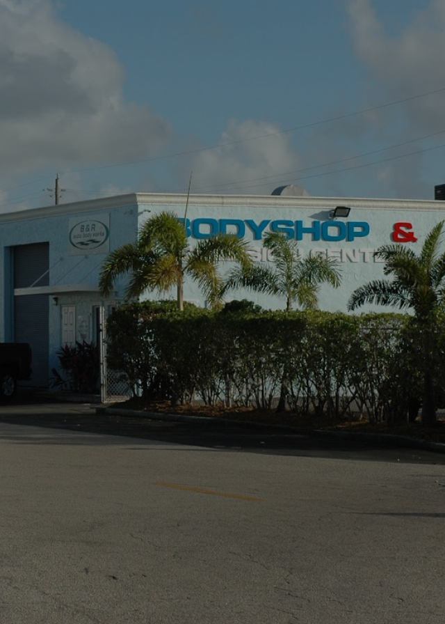 A body shop with palm trees in front of it | B & R Auto Body Works