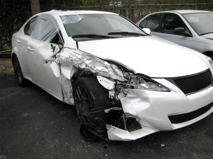 A white car with a damaged front end is parked in a parking lot | B & R Auto Body Works