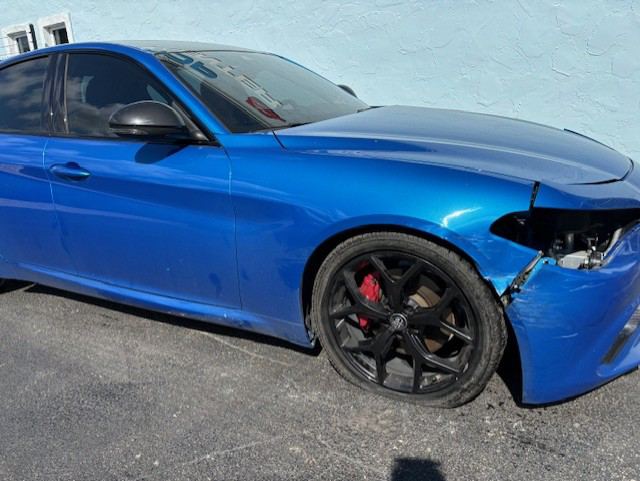 A damaged blue sports car is parked in a parking lot | B & R Auto Body Works