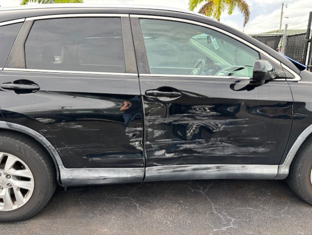 A black Honda CRV with a major dent parked in a parking lot | B & R Auto Body Works